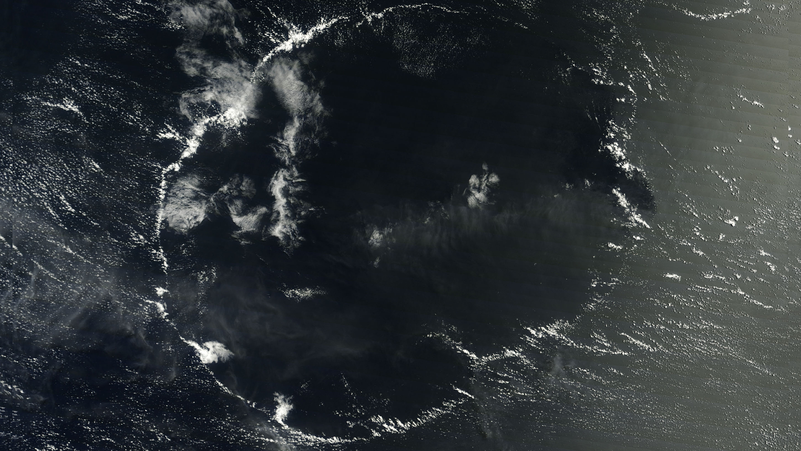 A satellite image of a thin wispy ring of clouds above the ocean